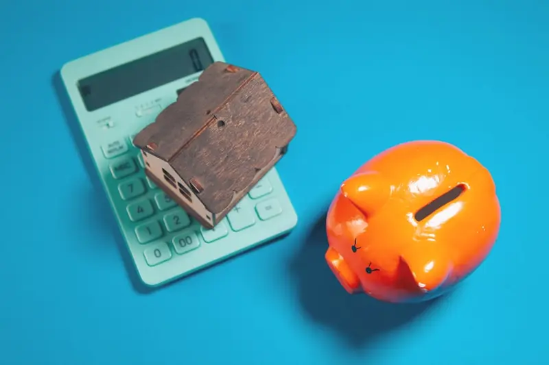 Calculator, piggy bank, and house model for home affordability planning